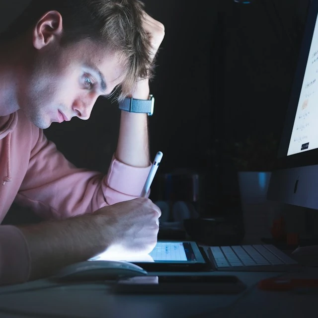 Man sitting in a dark room in front of a computer