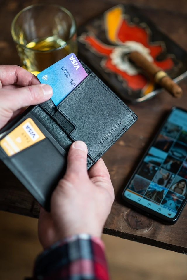 Hand holding a wallet with a a bunch of credit cards